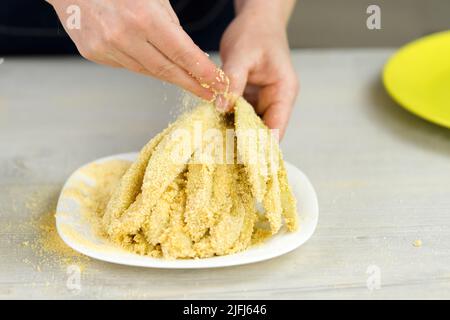 Beschichtung von geschnittener Aubergine mit Paniermehl. Frau kocht leckere Snacks zu Hause. Stockfoto