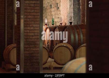 Weinkeller, unterirdischer Lagerraum mit kühlen Trockenmauern, mit authentischen alten Eichenfässern und Fässern für die Weinalterung Stockfoto