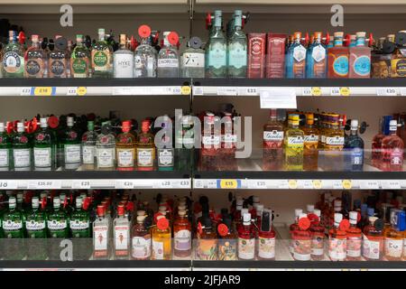 Farbenfrohe Flaschen mit Sicherheitskennzeichnung Gin zum Verkauf in Supermarktregalen bei Tesco. UK. Enthält spezielle und gängige Gins. Thema: Alkoholdiebstahl Stockfoto