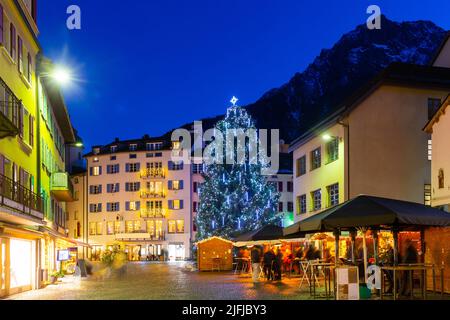 Nachtansicht der Brig Straße mit Weihnachtsbaum im Hintergrund der Alpen, Schweiz Stockfoto