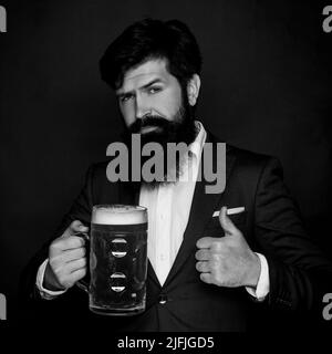 Fröhlicher Brauer. Bärtiger Mann mit einem Glas Bier. Bier in Großbritannien. Glücklicher lächelnder Mann mit Bier. Fröhlicher Brauer, der Glas mit Bier hält. Barkeeper. Alles gute Stockfoto