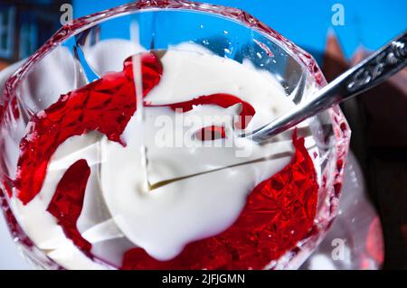 Rotes Gelee mit Creme in einer Kristallschüssel mit Besteck - Film Stockfoto