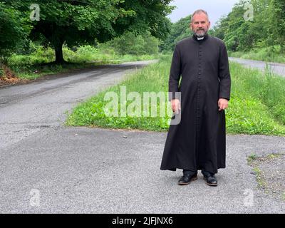 Centralia, USA. 17.. Juni 2022. Pater Francis DeRosa steht auf einer Straße in Centralia. Er geht durch die Stadt und ihre Geschichte und ist etwas erschrocken. Ein Kohlefeuer hatte die einst blühende Stadt im US-Bundesstaat Pennsylvania in eine Geisterstadt verwandelt. (Um dpa zu berichten: „Geisterstadt über einem Inferno“) Quelle: Benno Schwinghammer/dpa/Alamy Live News Stockfoto