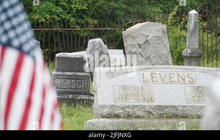 Centralia, USA. 17.. Juni 2022. Auf einem Friedhof in Centralia steht neben Grassteinen eine US-Flagge. Ein Kohlefeuer hatte die einst blühende Stadt im US-Bundesstaat Pennsylvania in eine Geisterstadt verwandelt. Kredit: Benno Schwinghammer/dpa/Alamy Live Nachrichten Stockfoto