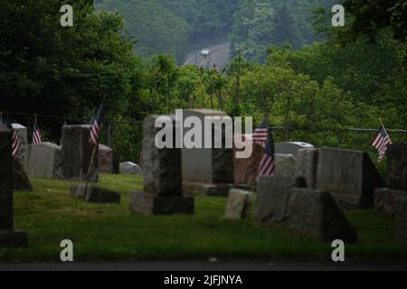 Centralia, USA. 17.. Juni 2022. Auf einem Friedhof in Centralia stehen US-Flaggen neben Grassteinen. Ein Kohlefeuer hatte die einst blühende Stadt im US-Bundesstaat Pennsylvania in eine Geisterstadt verwandelt. (Um dpa zu berichten: „Geisterstadt über einem Inferno“) Quelle: Benno Schwinghammer/dpa/Alamy Live News Stockfoto