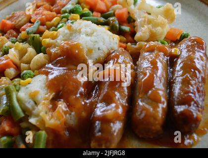 Würstchen mit Zwiebelsoße und Gemüse Stockfoto