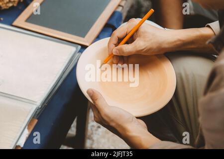 Künstler malen Skizze Zeichnung Sukhothai traditionellen Stil Muster auf Schale Steingut, Herstellung von handgemachten Keramik in Sukhothai, Thailand. Stockfoto