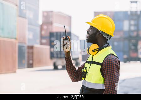 Schwarzer Arbeiter afrikanischen Arbeits Ingenieur Vorarbeiter Funksteuerung in Hafen Fracht Versand Zoll Containerhof Stockfoto