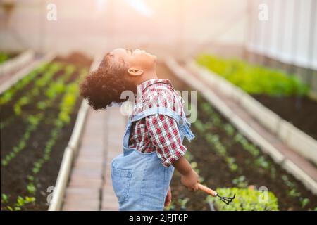 Glück Kind kleines Mädchen genießen glücklich spielen, wie Landwirt Pflanzen den Baum in Gemüsegarten Bauernhof Stockfoto