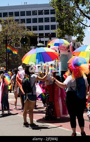 Menschen, die an der Pride Parade in San Francisco teilnehmen und Regenbogenschirme tragen, um ihre Unterstützung zu zeigen. Stockfoto