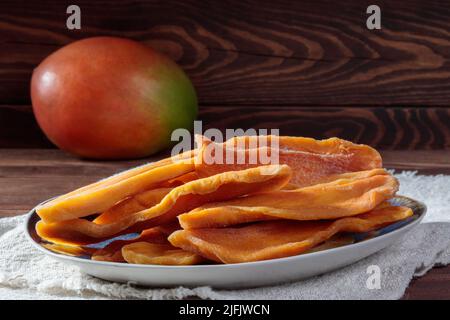 Nahaufnahme von getrockneten Mangoscheiben auf einem Teller mit Mango. Stockfoto