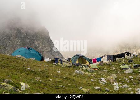 Kleidung an der Wäscheleine nach dem Regen in den Bergen. Zelte im Touristenlager. Stockfoto