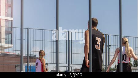 Ein Team von Studenten spielt im Sommer auf einem Sportplatz auf dem Campus im Freien Basketball Stockfoto