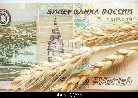 Rubel-Banknote und ukrainischer Weizen auf weißem Hintergrund, Getreidediebstahl durch Russland in der Ukraine Stockfoto