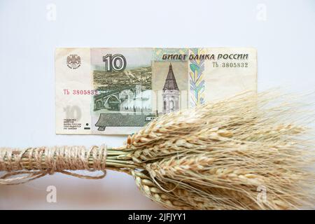 Rubel-Banknote und ukrainischer Weizen auf weißem Hintergrund, Getreidediebstahl durch Russland in der Ukraine Stockfoto