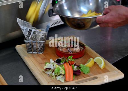 Serviert in einem Ramekin auf einem Holzbrett mit Salat und pommes frites Stockfoto
