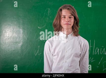 Schuljunge in einem weißen Hemd, der im Klassenzimmer an der Tafel antwortet Stockfoto