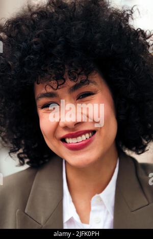 Junge lächelnde lateinerin mit lockigen afro Haaren Stockfoto