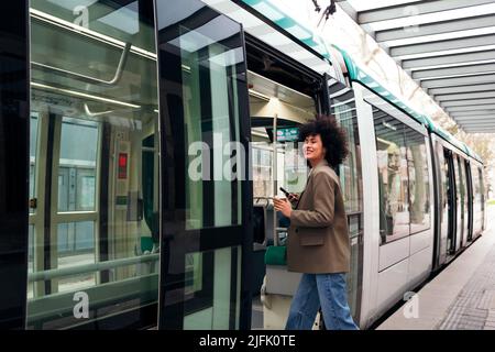Lächelnde Geschäftsfrau, die die Straßenbahn betrat Stockfoto