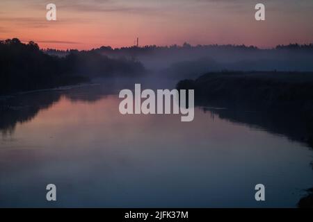Dämmerungslandschaft: Der Neman River an einem Sommerabend, Nebel über der Wasseroberfläche. Stockfoto
