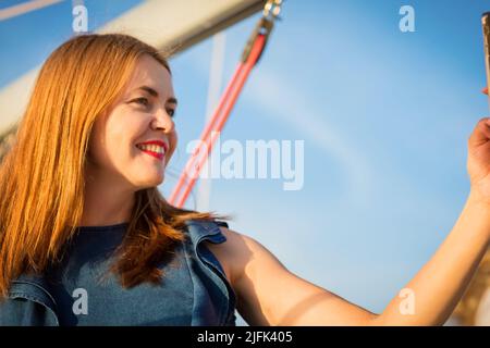 Attraktive Frau, die Selfie-Fotos auf dem Smartphone macht, während sie auf der Yacht steht Stockfoto