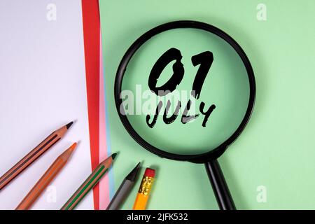1. Juli. Schwarze Lupe und Bürobedarf auf grünem Hintergrund. Stockfoto