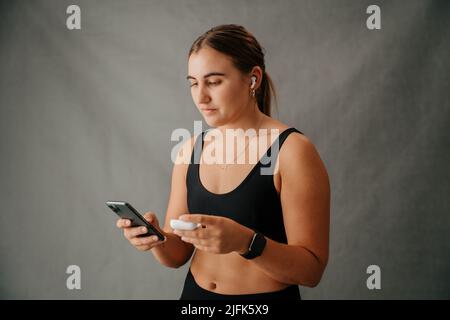 Nahaufnahme einer Frau auf ihrem Handy mit ihren Ohrkissen Stockfoto