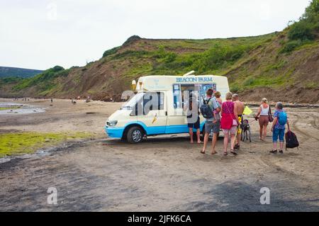 Leute, die sich in einem Van am Strand in Robin Hood's Bay, North Yorkshire, für Eis anstellen Stockfoto