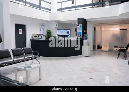 Keine Menschen im Wartebereich für Patienten mit Arztterminen in moderner Gesundheitsklinik in der Privatpraxis hopital. Leerer Warteraum mit Rezeption mit Werbeflyers. Stockfoto