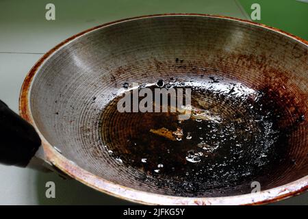 Nahaufnahme von verbrannten, verbrannten und fettigen Pfanne oder Wok mit Speiseöl in der Küche. Stockfoto