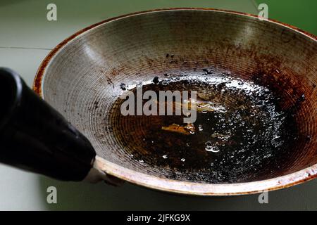 Nahaufnahme von verbrannten, verbrannten und fettigen Pfanne oder Wok mit Speiseöl in der Küche. Stockfoto