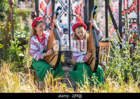 Hampton Court Palace, Surrey, Großbritannien. 4. Juli 2022. RHS Hampton Court Palace Garden Festival Pressetag für die größte Blumenschau der Welt, die bis zum 9. Juli 2022 stattfindet. Bild: Global Impact Garden: Traditionelle ukrainische Band tritt hinter Weizenfeldern auf dem von Victoria Manoylo und Carrie Preston entworfenen „What does Not Burn Garden“ auf, einer Destillation der ukrainischen Landschaft und Kultur. Es zeigt den Rushnyk, ein besticktes Tuch, das in vielen Ritualen verwendet wird, als Symbol des Lebens und der Identität. Wie eine neue Haut schmücken Rushnyks die Überreste einer verbrannten Hütte, die als Silhouette in der Landschaft steht. Kredit: Ma Stockfoto