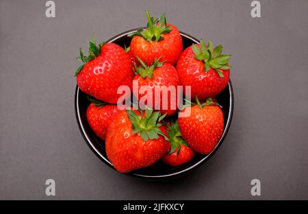 Frisch gepflückte englische Erdbeeren in einer Schüssel auf braunem Hintergrund Stockfoto