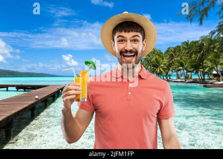 Fröhlicher Mann in Strohhut mit Orangensaft-Cocktail Stockfoto