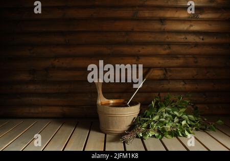 Ein Birkenbad-Schneebesen (Vihta) und ein Wassereimer, bereit für Badegäste in einer finnischen Sauna. Platz für Kopien. Stockfoto