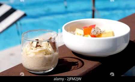 Gesundes veganes Essen - exotischer Obstsalat mit Papaya, Drachenfrucht und Apfel, Haferflocken mit Müsli, Mandelnüssen und Rosinen. Gesundes Frühstück Stockfoto