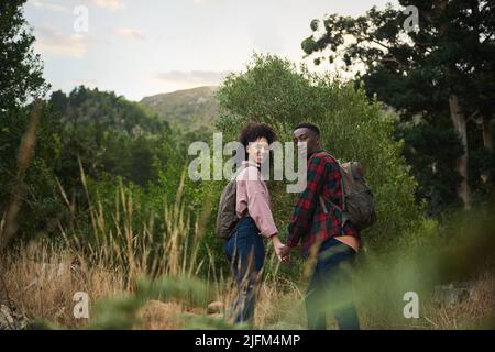 Lächelndes junges multiethnisches Paar, das auf einer Wanderung in einigen Hügeln zusammen ist Stockfoto