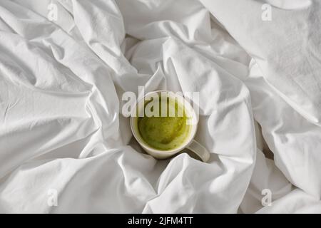 tasse Matcha-Tee im Bett zu Hause Stockfoto