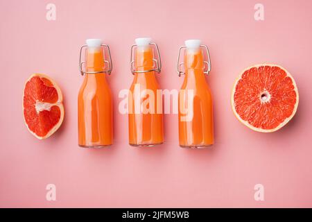 Frisch gepresster Grapefruitsaft, auf rosa strukturiertem Sommerhintergrund, Draufsicht flach liegend Stockfoto