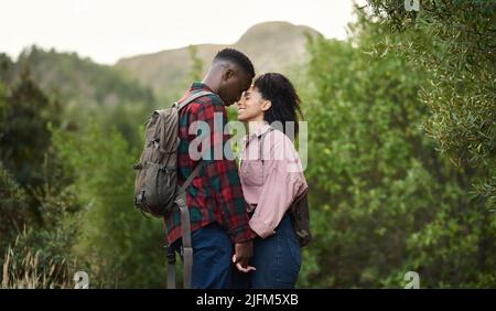 Liebevolles multiethnisches Paar, das mit geschlossenen Augen auf einem Wanderweg steht Stockfoto