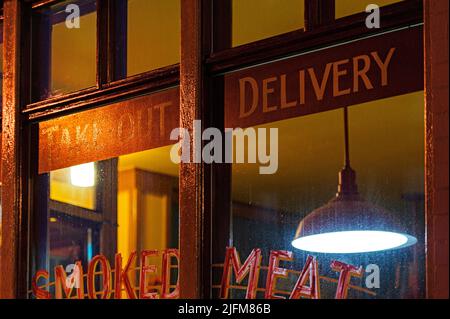Mitnahme und Lieferung plus Rauchfleisch Zeichen in der Witwe eines 1950s Stil Diner Stockfoto