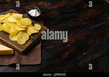 Wellige, leicht gesalzene Kartoffelchips auf altem dunklen Holztisch mit Platz für Text Stockfoto