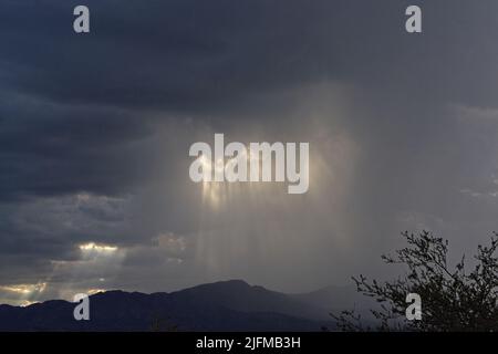 Gewitterwolken über den Bergen mit einstrahlenden Sonnenstrahlen. Stockfoto