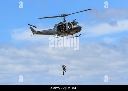 Ein Bell UH-1 Iroquois 'Huey' Hubschrauber der Royal New Zealand Air Force, der einen Mann an einem Seil absenkt Stockfoto