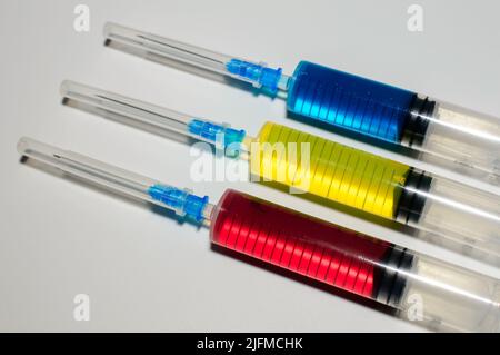 Baummedizinische Spritzen mit farbiger Farbe in roten, gelben und blauen Farben auf weißem Hintergrund. Impfung gegen Corona-Virus und Monkepox. Stockfoto