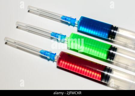 Baummedizinische Spritzen mit farbiger Farbe in roten, gelben und blauen Farben auf weißem Hintergrund. Impfung gegen Corona-Virus und Monkepox. Stockfoto