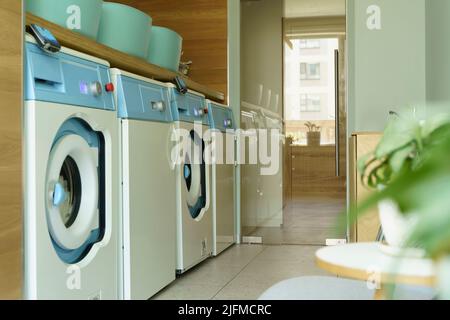 Waschküche innen. Waschmaschinen und Trockner in einem hellen, sonnigen Waschraum. Hochwertige Fotos Stockfoto