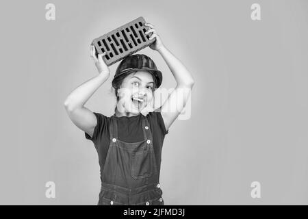 Fröhliche Kinderarbeiter mit Gebäude Uniform und Ziegel, Gebäude Stockfoto