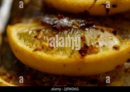 Makrofoto einer Zitrone mit Gewürzen auf der Oberseite des dorado-Fisches. Goldener Spar Fisch mit den Zitronen bedeckt. Stockfoto