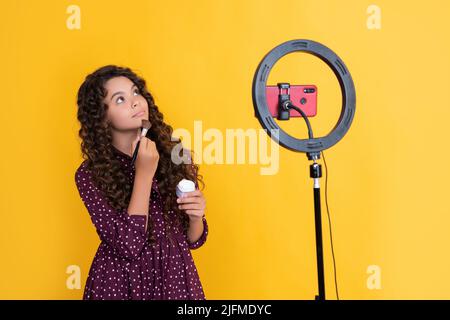 Glückliches Mädchen mit langen lockigen Haaren macht Video für Blog halten Puderbürste Stockfoto